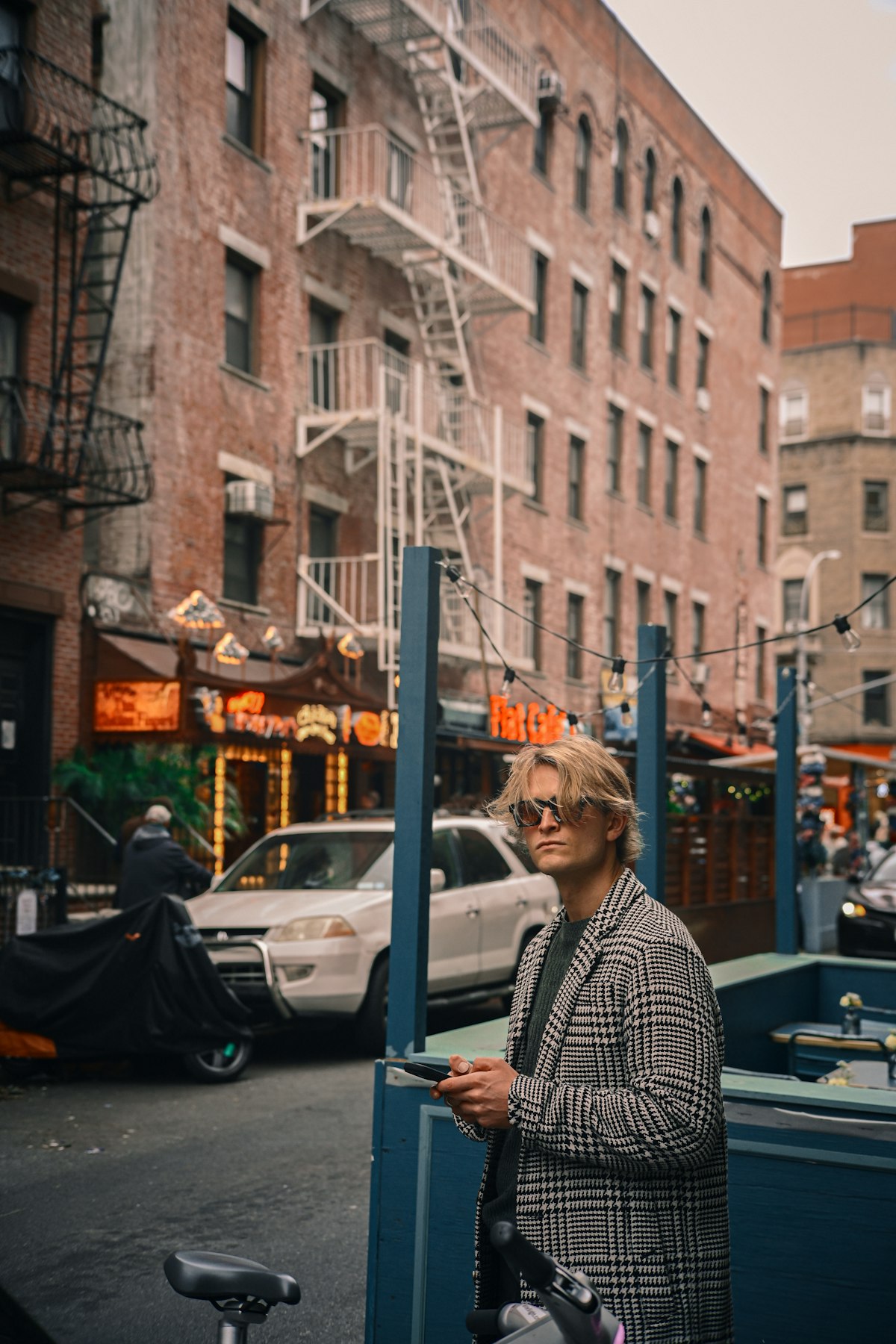 An older man in a plaid jacket reading his phone on a city street